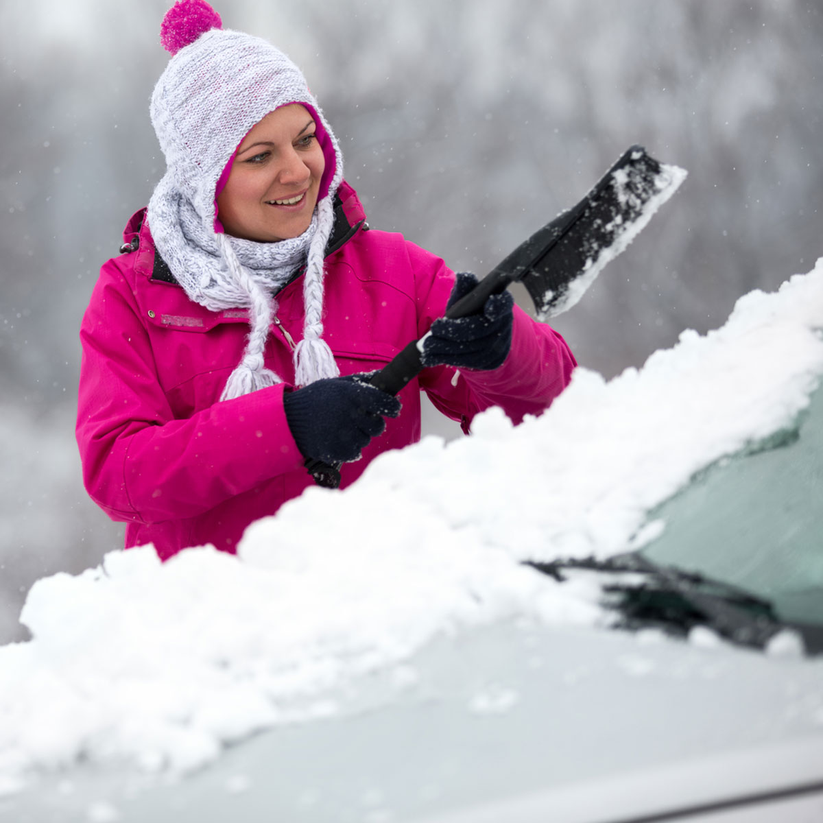 Woman removing snow from windshield